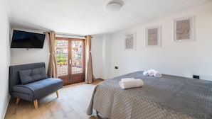 Une chambre avec un lit, un canapé, une télévision et un balcon.