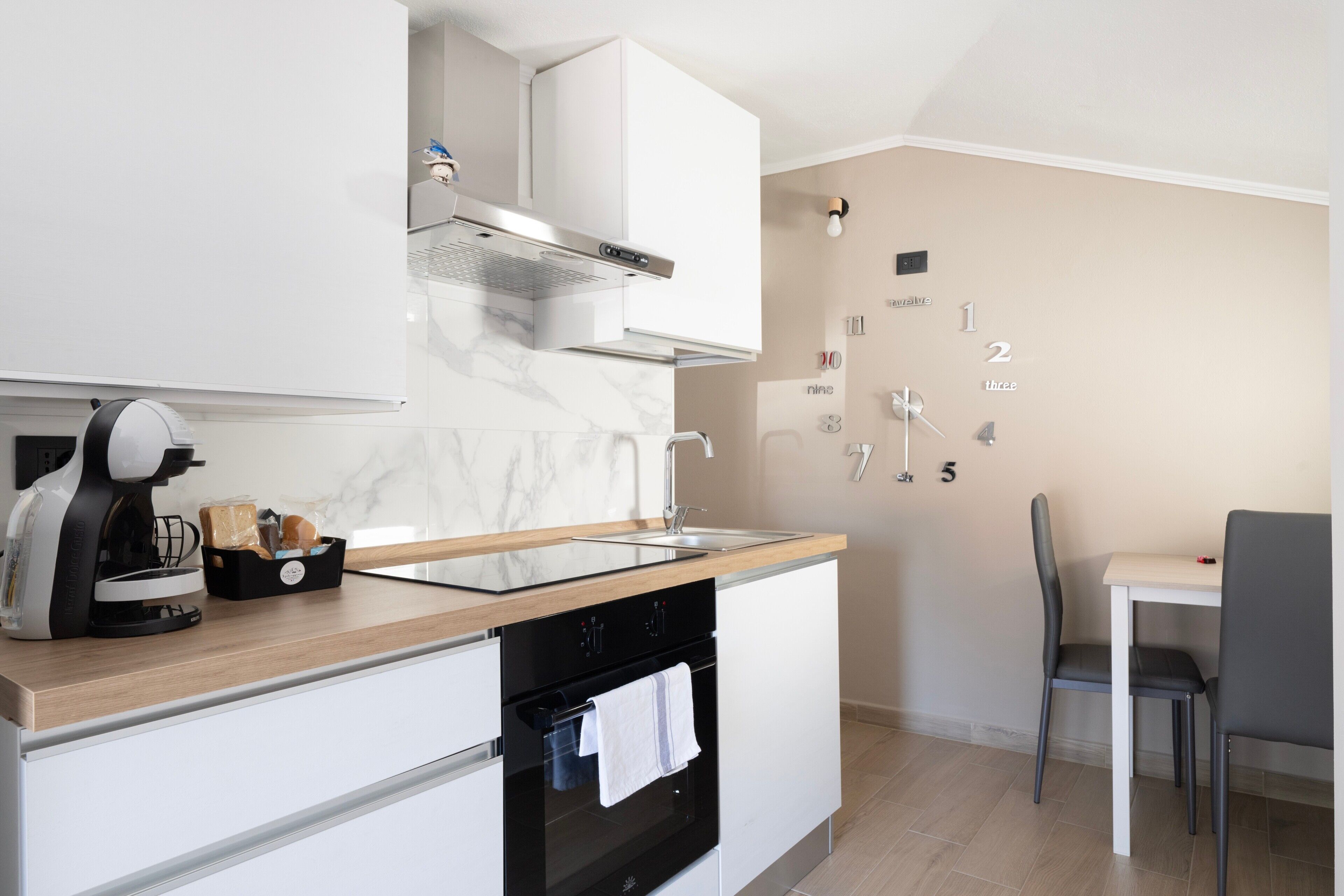 Una cucina moderna con forno integrato, macchina del caffè e pannello di schienale in marmo.