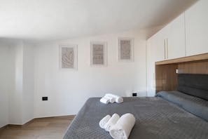 A bedroom with a bed, a wooden headboard, and three framed artworks on the wall.