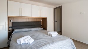 Un lit bien fait, avec une couverture matelassée, une tête de lit en bois et une armoire blanche à deux portes.