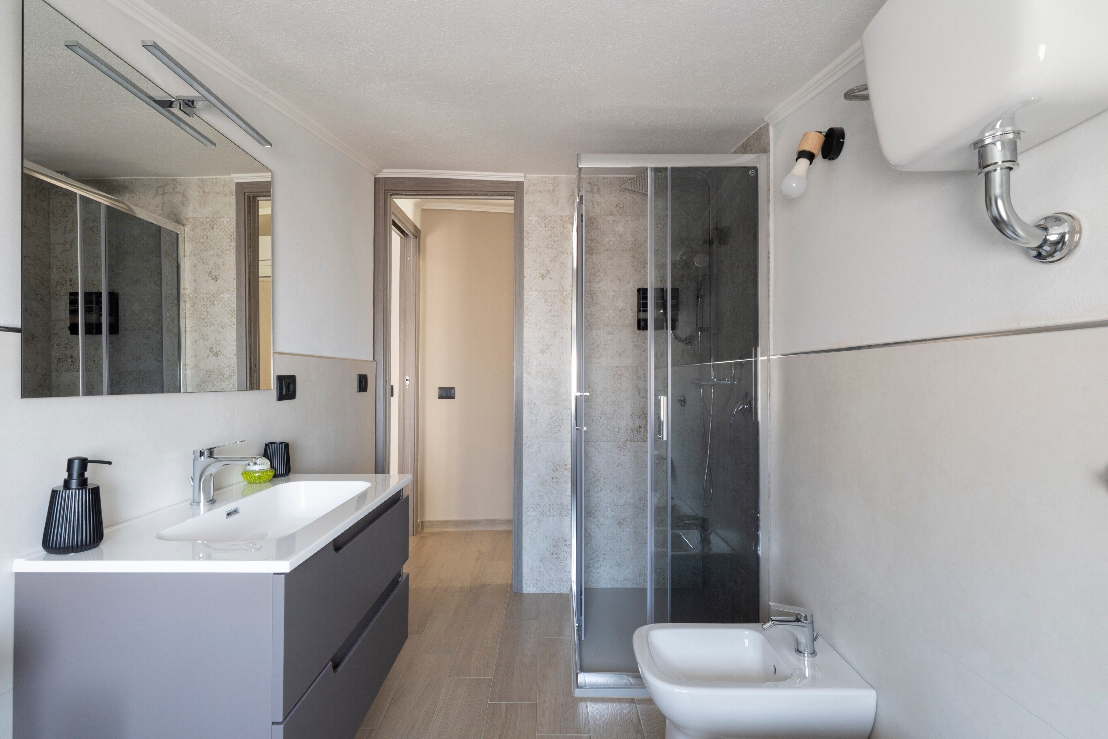 Een moderne badkamer met een douchecabine van glas, een wastafel en een toilet.