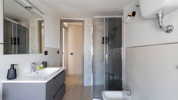 Een moderne badkamer met een douchecabine van glas, een wastafel en een toilet.