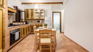 A kitchen with wooden cabinets, a dining table, and a built-in oven. - Aurora Sul Mare Apartment with Wi-Fi and Air Conditioning (Palermo)