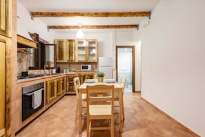 Cozinha com armários de madeira, mesa de jantar e forno embutido.