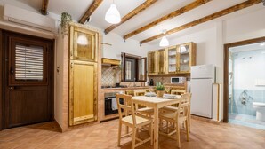 A kitchen with wooden cabinets, a dining table with chairs, and a refrigerator. - Aurora Sul Mare Apartment with Wi-Fi and Air Conditioning (Palermo)