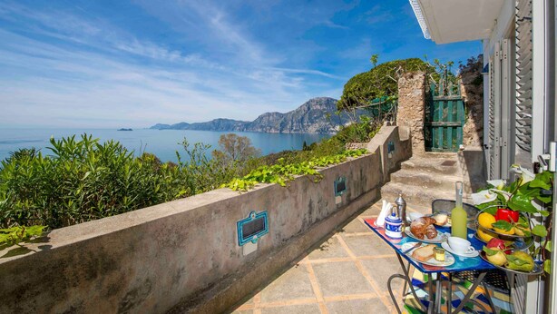 Ein Balkon mit Frühstückstisch und Blick auf eine malerische Küstenlandschaft.