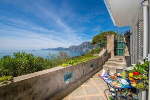 A balcony with a table set for breakfast overlooking a scenic coastal view. - Apartment 'Il Geco Praiano' with Sea View, Wi-Fi and Air Conditioning (Praiano)