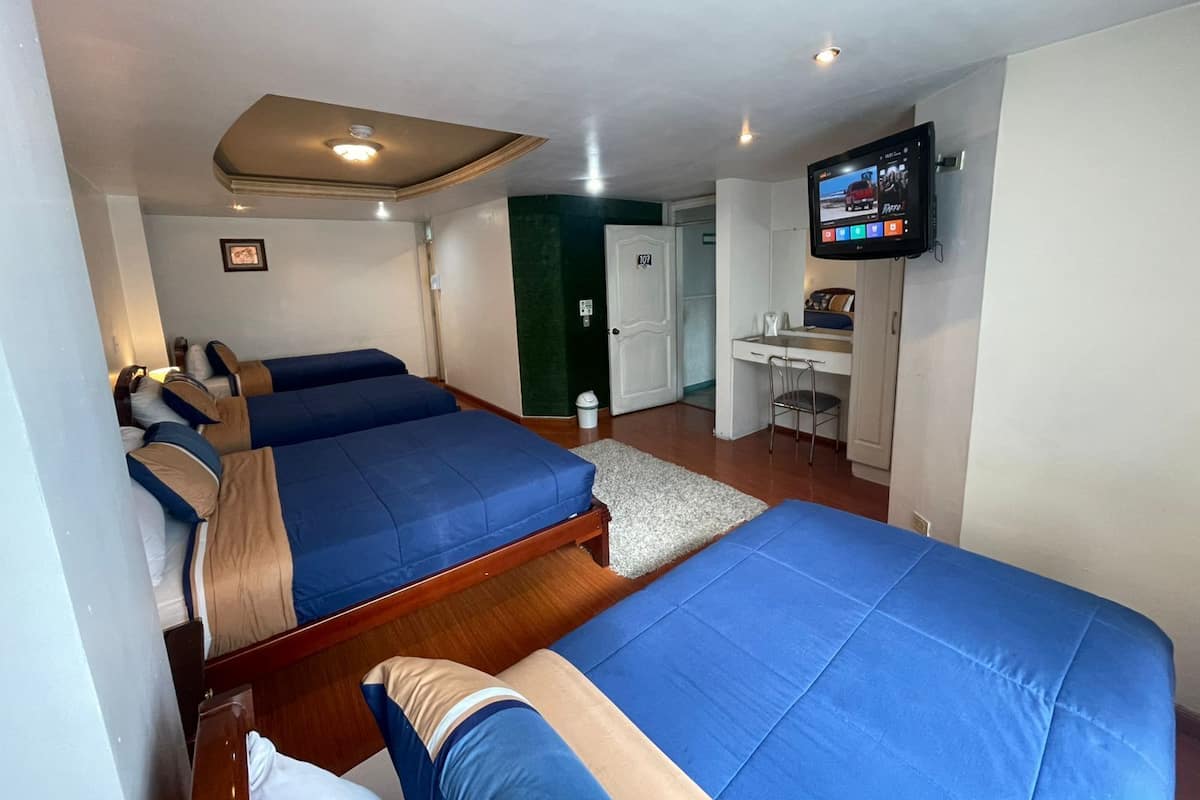 A hotel room with three beds, a desk, a TV, and a door marked with the number 107.