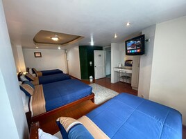 Habitación de hotel con tres camas, un escritorio, un televisor y una puerta con el número 107.