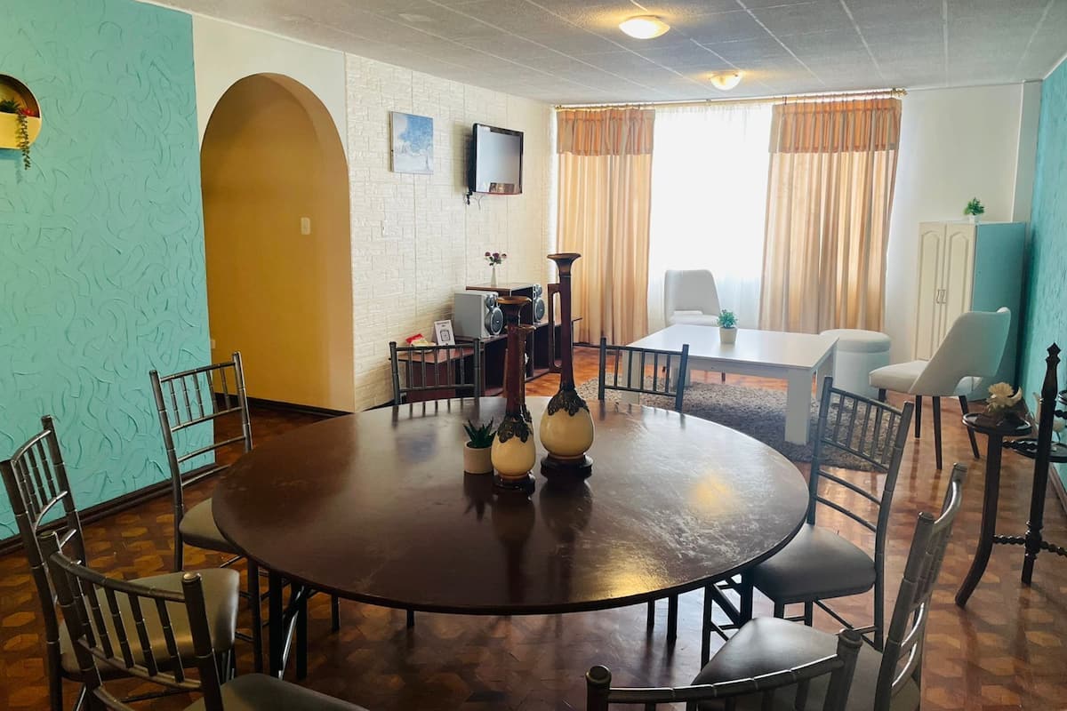 A dining area with a round table, chairs, a television, and a cabinet.