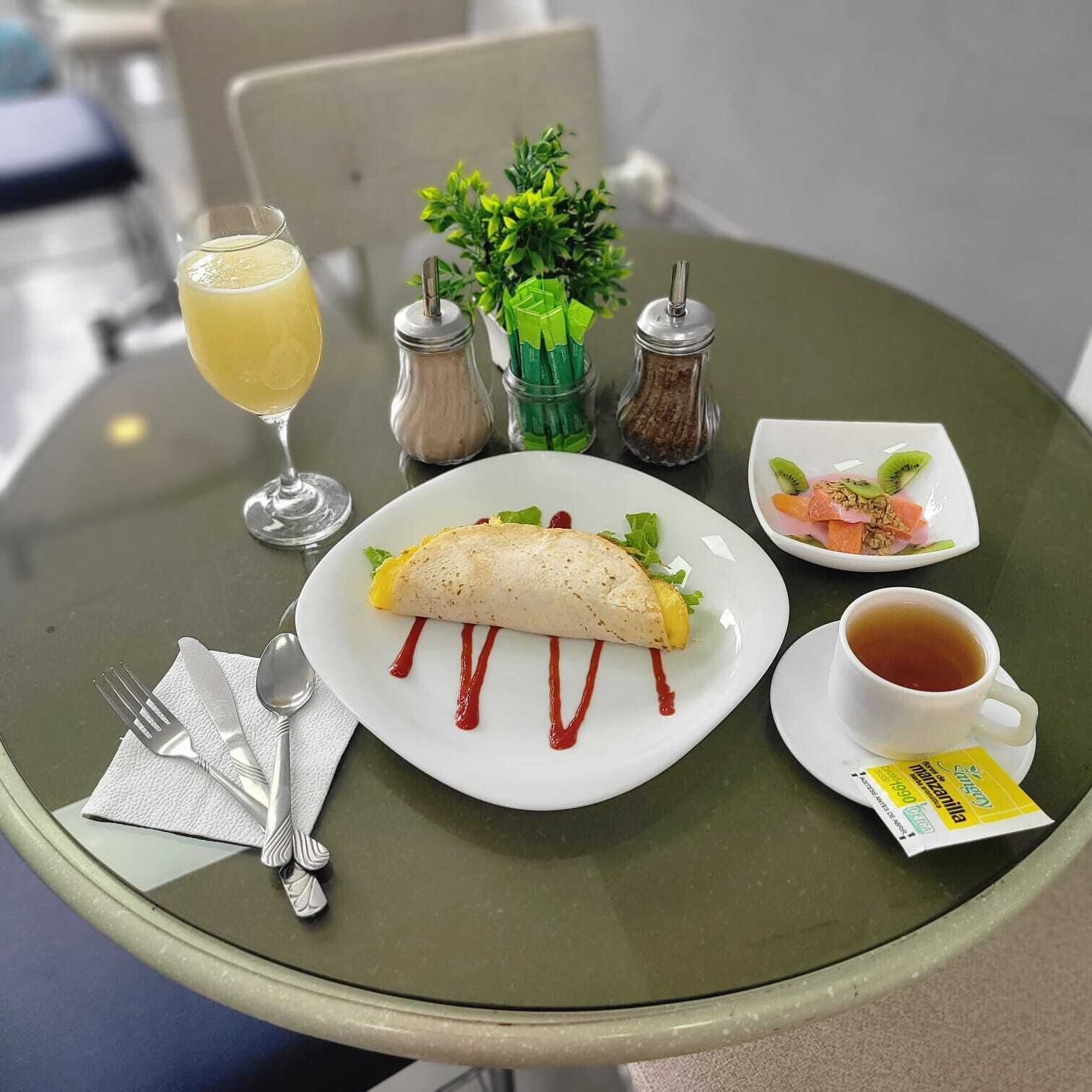 A table with a plate of food, a glass of drink, and condiments.