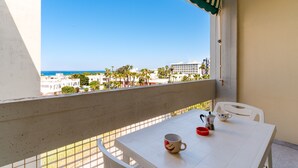 Ein Balkon mit einem weißen Tisch, einer roten Schüssel und einer weißen Tasse.