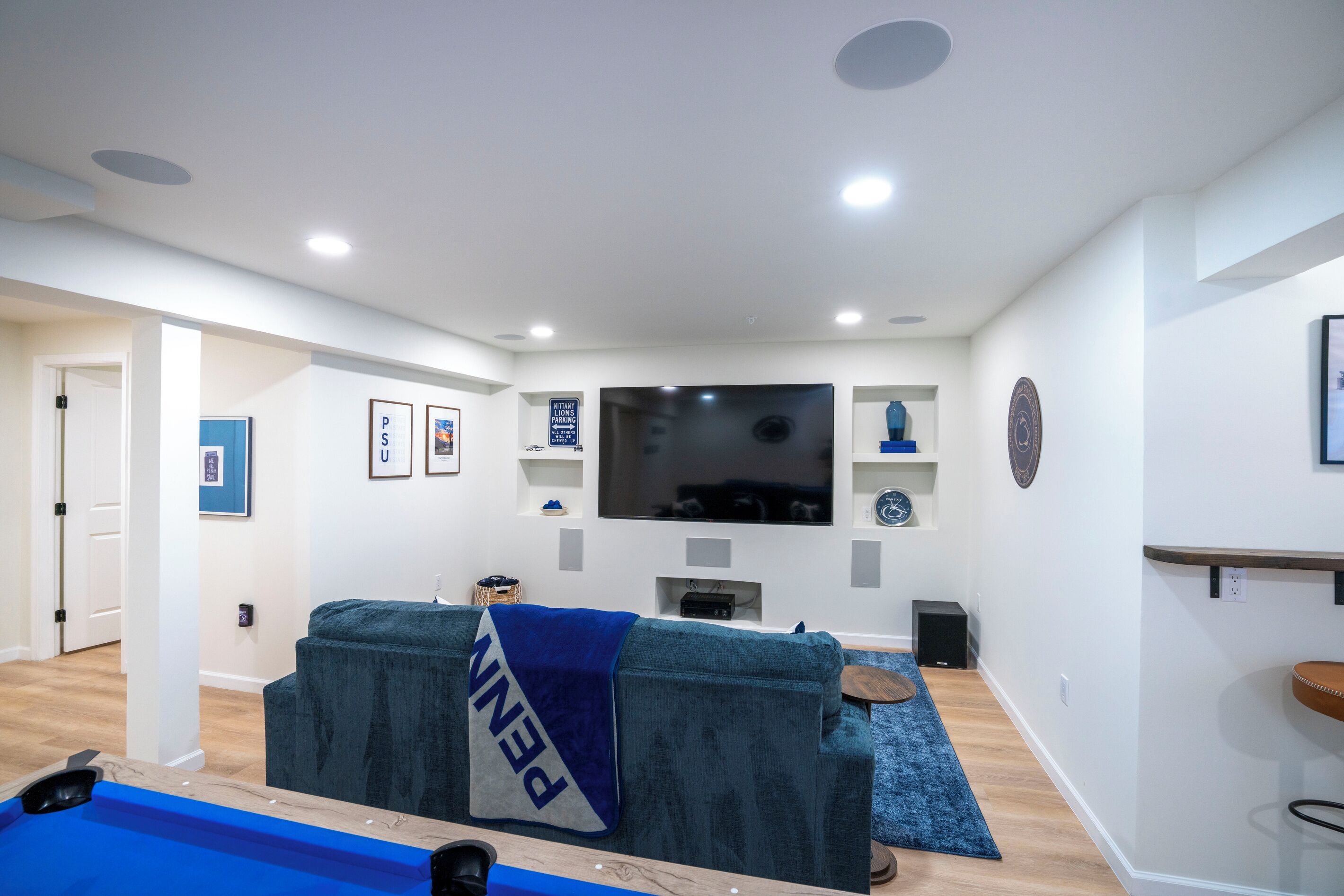 A living room with a large flat-screen TV, a blue couch, a coffee table, and a blue rug.