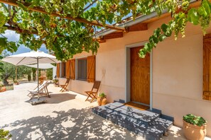 A building with a wooden pergola, outdoor seating, and a door.