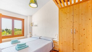 A bedroom with a large bed, wooden wardrobe, and a window with a view. - Country House 'Lluna' with Mountain View, Shared Pool and Wi-Fi (Ibi)