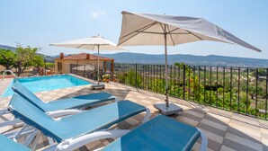 A pool area with blue lounge chairs and white umbrellas, a small building, and a view of the countryside. - Country House 'Sol' with Mountain View, Shared Pool and Wi-Fi (Ibi)