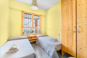 A room with two beds, a wooden wardrobe, a window with bars, and a hanging light fixture. - Country House 'Sol' with Mountain View, Shared Pool and Wi-Fi (Ibi)
