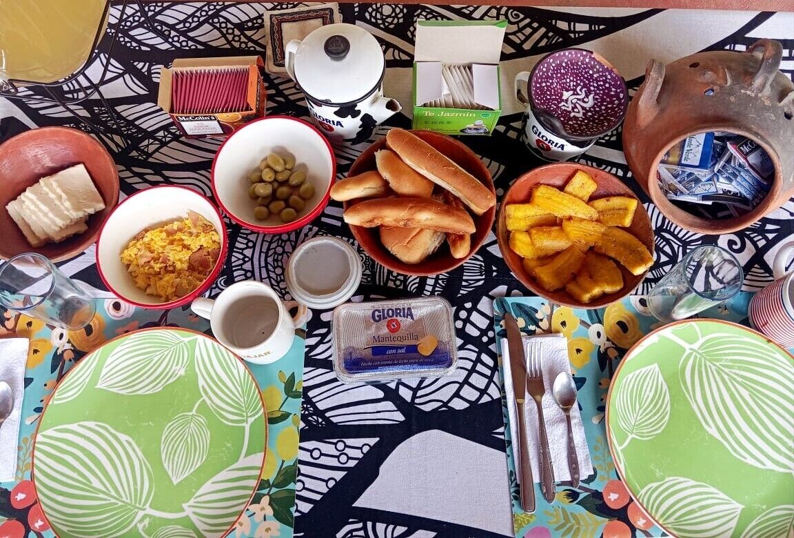 Une table garnie de divers aliments et condiments, notamment du pain, des olives et un récipient contenant du fromage.