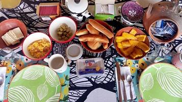 Une table garnie de divers aliments et condiments, notamment du pain, des olives et un récipient contenant du fromage.