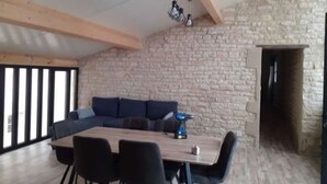 A dining area with a stone wall, a wooden ceiling, and a large table with chairs. - Country House 'Domaine du Val Bruant' with Shared Terrace and Wi-Fi (Arc-en-Barrois)