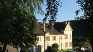 A two-story building with a symmetrical facade, a central entrance, and a driveway leading to parked cars. - Country House 'Domaine du Val Bruant' with Shared Terrace and Wi-Fi (Arc-en-Barrois)