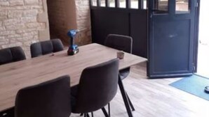 A conference room with a wooden table, black chairs, and a stone wall. - Country House 'Domaine du Val Bruant' with Shared Terrace and Wi-Fi (Arc-en-Barrois)