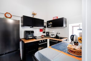 Cozinha compacta com geladeira, micro-ondas, cafeteira e pia.