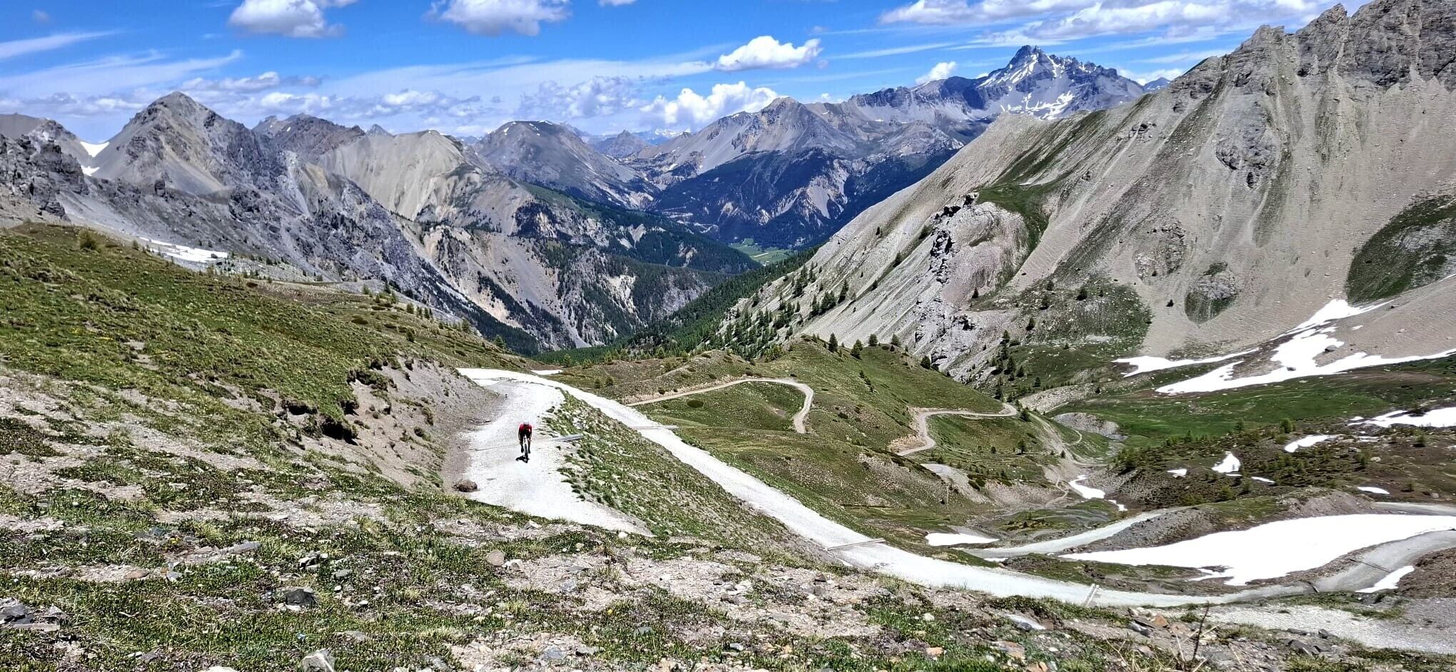 A mountainous landscape with a winding road, rocky terrain, and sparse vegetation.