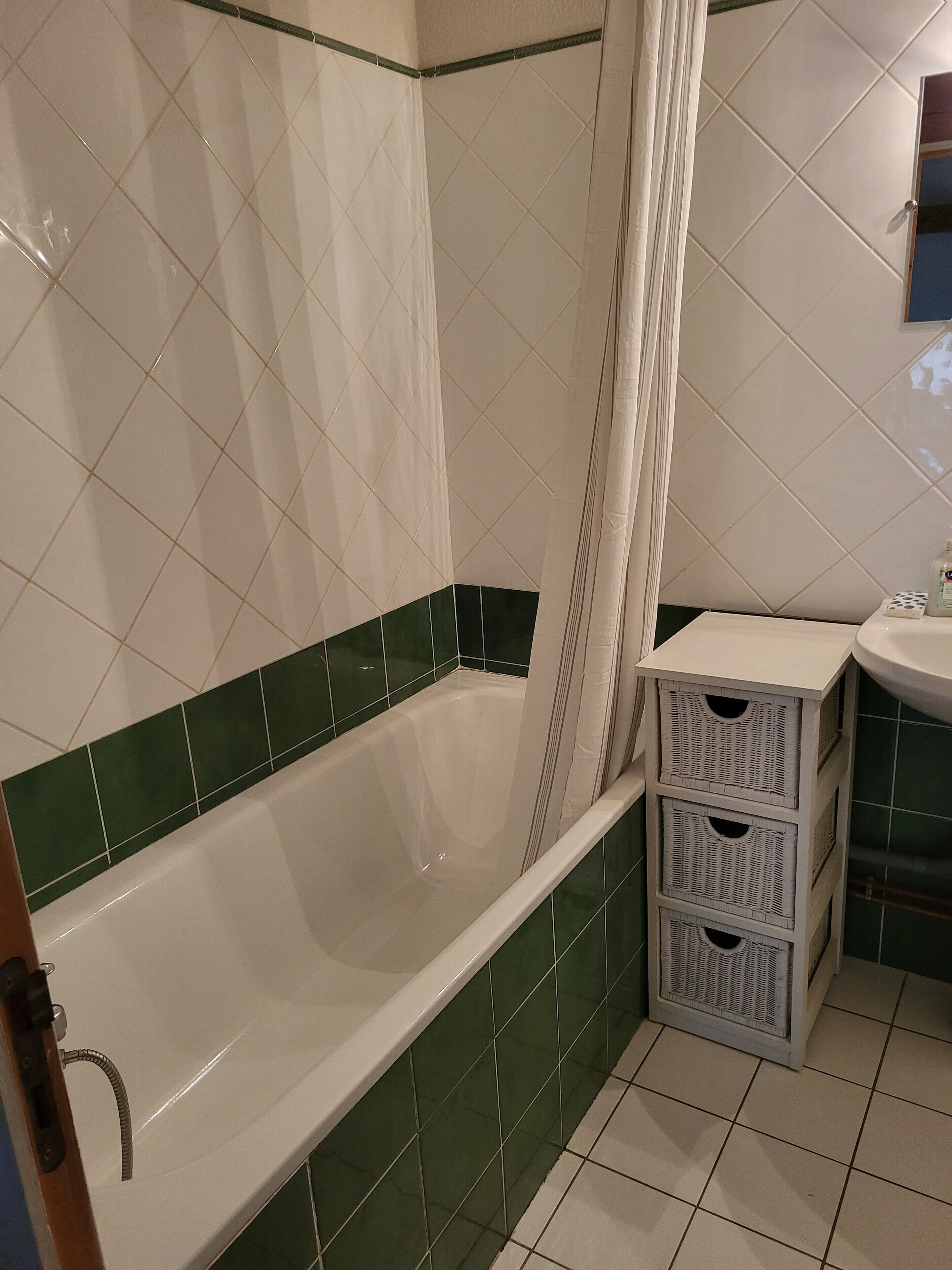 Ein Badezimmer mit Badewanne, Duschvorhang, Waschbecken und Spiegel.