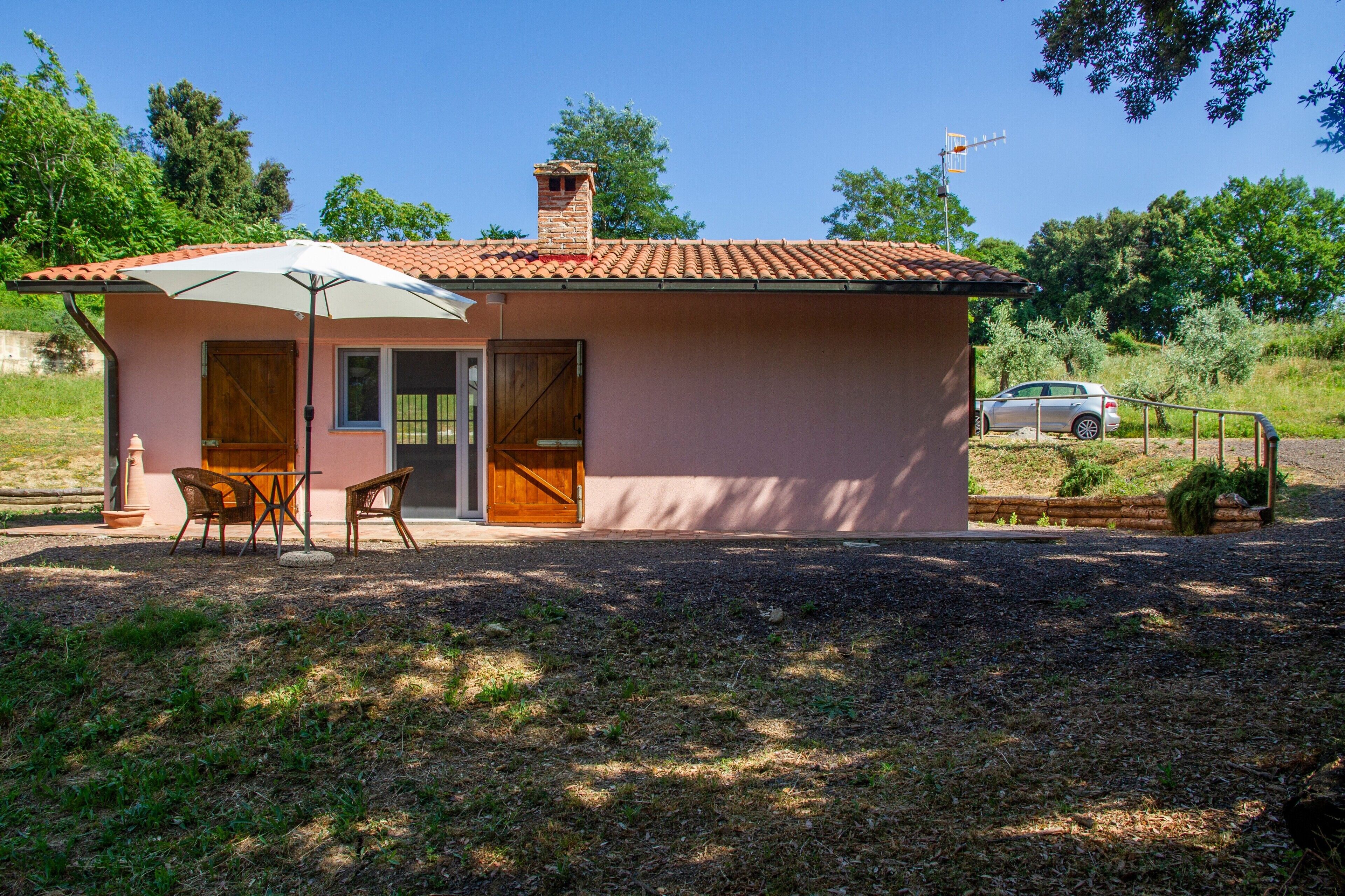 A small house with a tiled roof, a wooden door, and a patio with chairs.