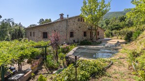 Un edificio de piedra con jardín y fuente.