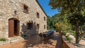 Un edificio de piedra con patio, mobiliario exterior y piscina.