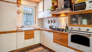 A modern kitchen with white cabinets, wooden countertops, a built-in oven, and a window providing natural light. - Apartment 'Re 1' with Balcony, Wi-Fi and Air Conditioning (Trento)