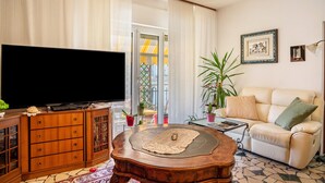 A living room with a television, wooden cabinet, coffee table, sofa, and potted plants. - Apartment 'Re 1' with Balcony, Wi-Fi and Air Conditioning (Trento)