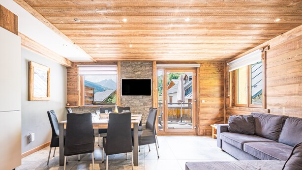 A modern interior with a dining area, a flat-screen TV, and a sofa.