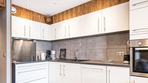 A modern kitchen with white cabinets, a stainless steel refrigerator, and a built-in oven.