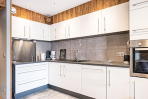 A modern kitchen with white cabinets, a stainless steel refrigerator, and a built-in oven. - Apartment 'Le Crey Rond' with Mountain View, Private Terrace and Wi-Fi (Valloire)