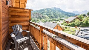 A wooden balcony with a view of a mountainous landscape.