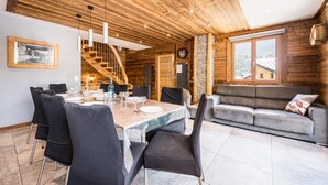 A wooden interior with a dining table set for four, a sofa, and a staircase. - Apartment "Le Galibier" with Mountain View, Balcony and Wi-Fi (Valloire)