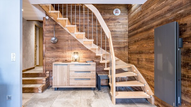 A modern interior with a wooden staircase, a wooden wall panel, a kitchen area with a refrigerator, and a bench. - Apartment "Le Galibier" with Mountain View, Balcony and Wi-Fi (Valloire)
