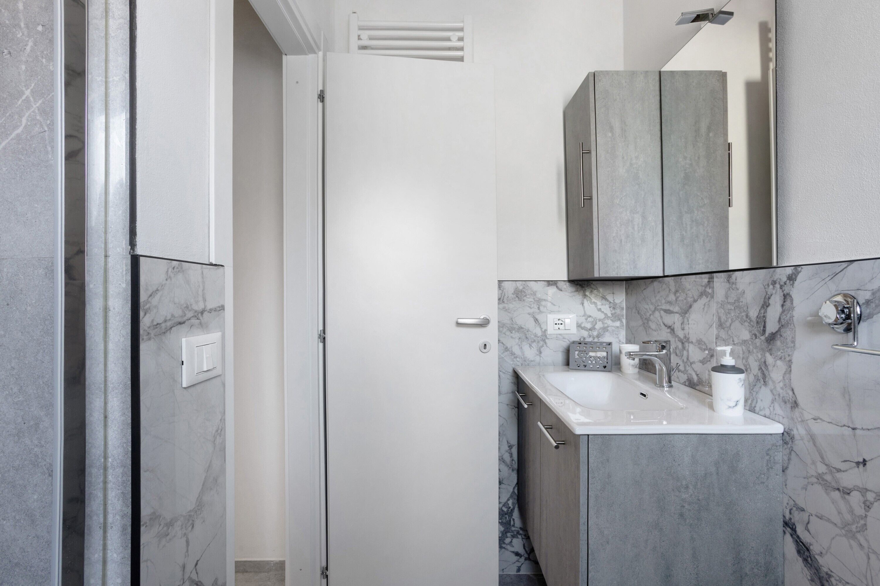 A bathroom with a marble sink, a mirror, and a cabinet.