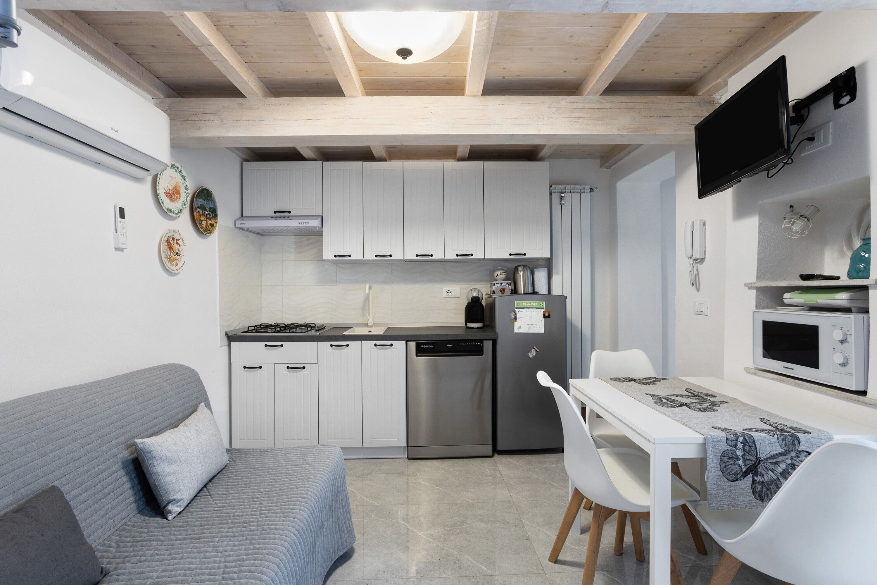 A compact kitchen with white cabinets, a dishwasher, a refrigerator, and a dining area with a table and chairs.