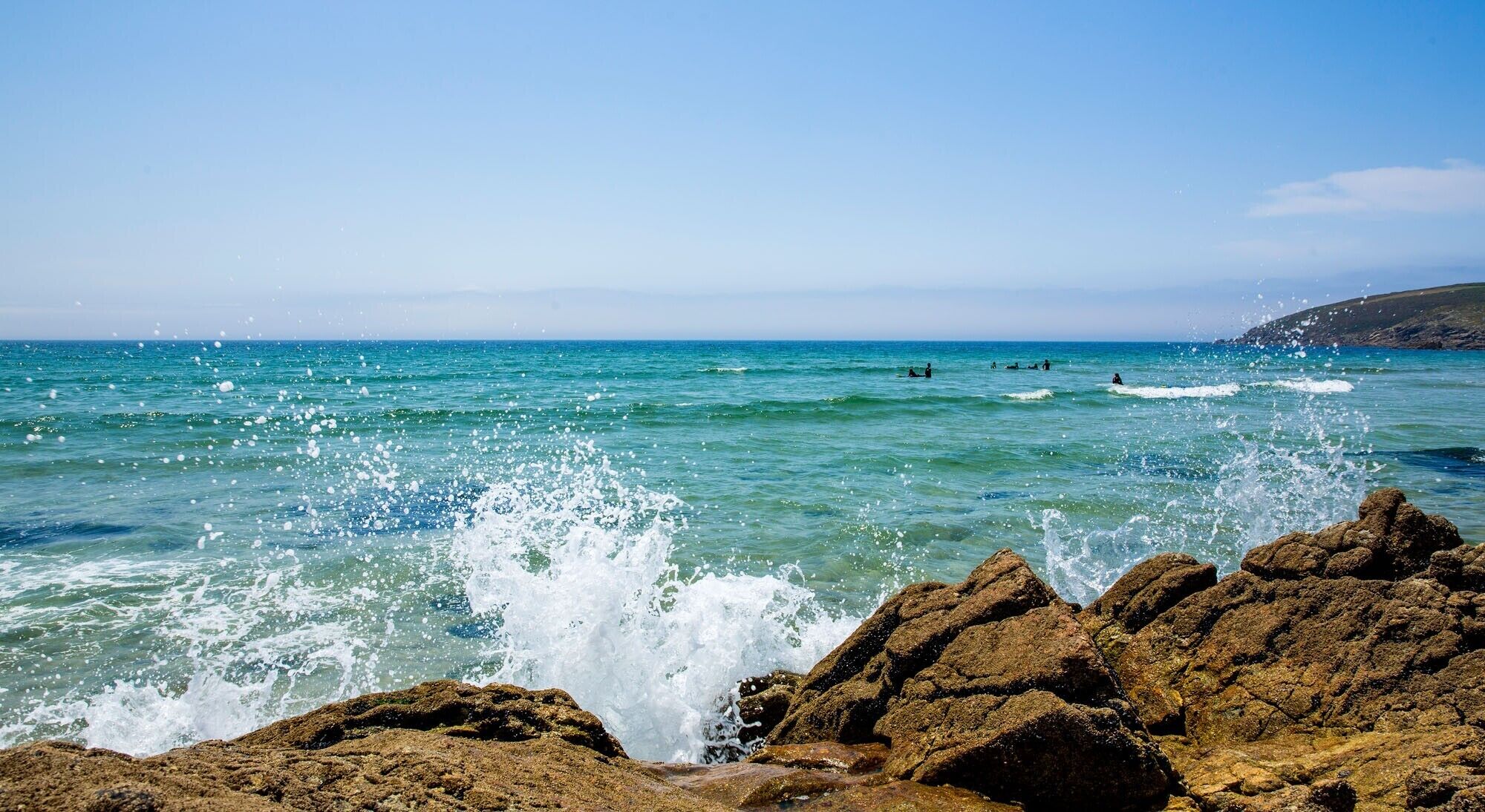 Un rivage rocheux où les vagues s’écrasent contre les rochers.