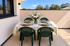 A table set for four with a floral centerpiece, green chairs, and a beige wall in the background. - Casa Muxía – Your Retreat on the Costa da Morte: Garden, Barbecue, Beach 2 km Away (Unknown)