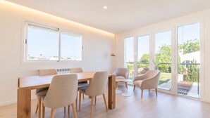A spacious room with a wooden dining table, four chairs, a small round table, and a large sliding glass door leading to an outdoor area. - Apartment 'Las Palmeras 1' with Shared Pool, Wi-Fi and Air Conditioning (Cala Millor)