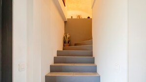 A staircase with a handrail, a light fixture above, and a plant on the landing. - Chambre d’hôtes Chêne with Air Conditioning – Serenity, Nature and Well-being in Gascony (Mauléon-d'Armagnac)