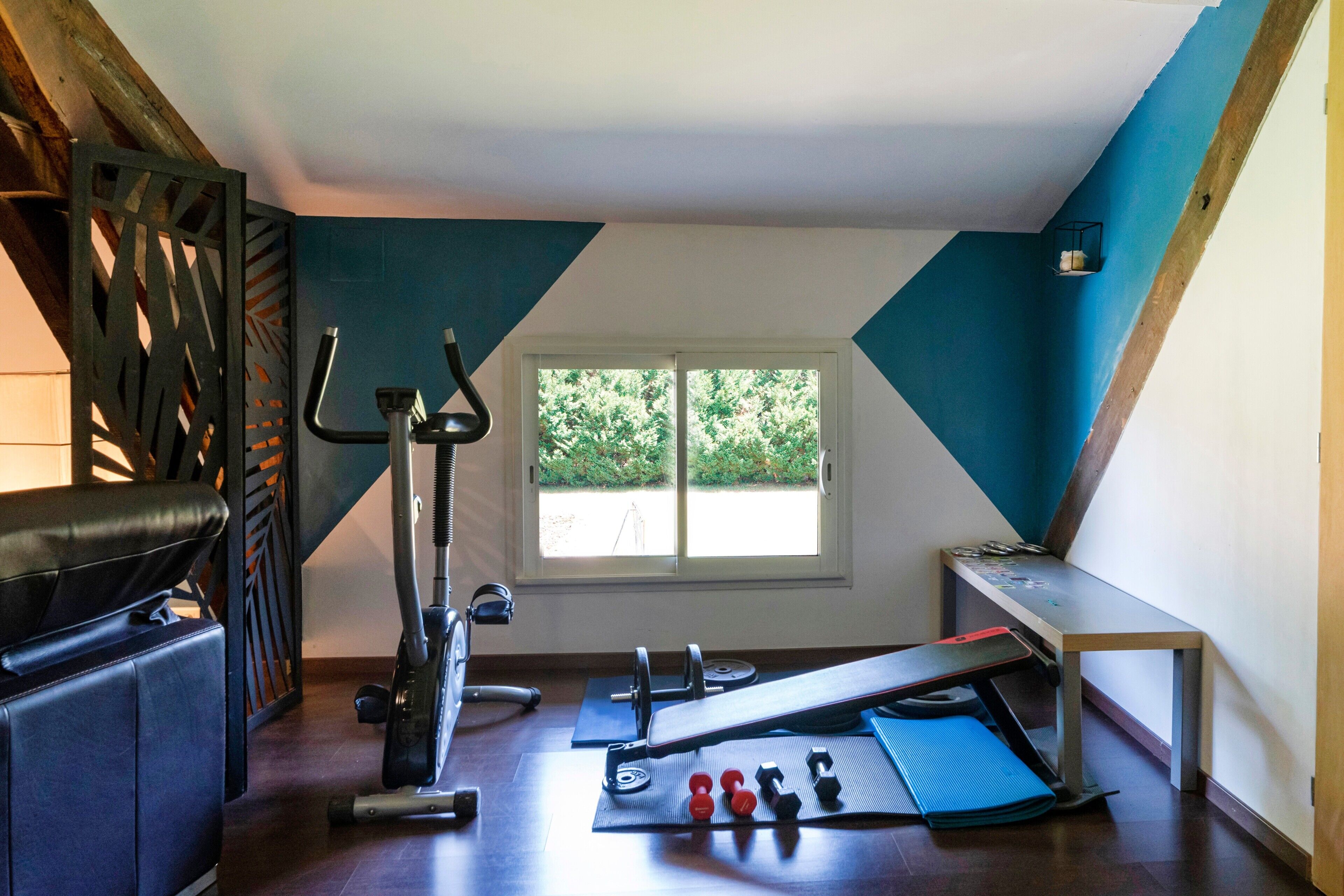 Ein Fitnessraum mit Trainingsgeräten, einer Bank und einem Fenster mit Blick.