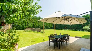 An outdoor patio with a table and chairs, a large umbrella, and a potted plant. - Chambre d’hôtes Chêne with Air Conditioning – Serenity, Nature and Well-being in Gascony (Mauléon-d'Armagnac)