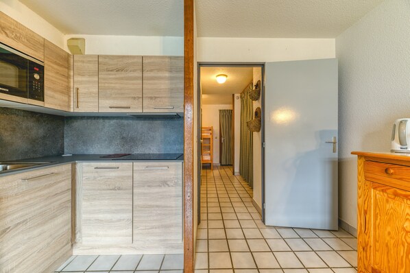Una cocina moderna con armarios de madera, un microondas Bosch y piso de baldosas.