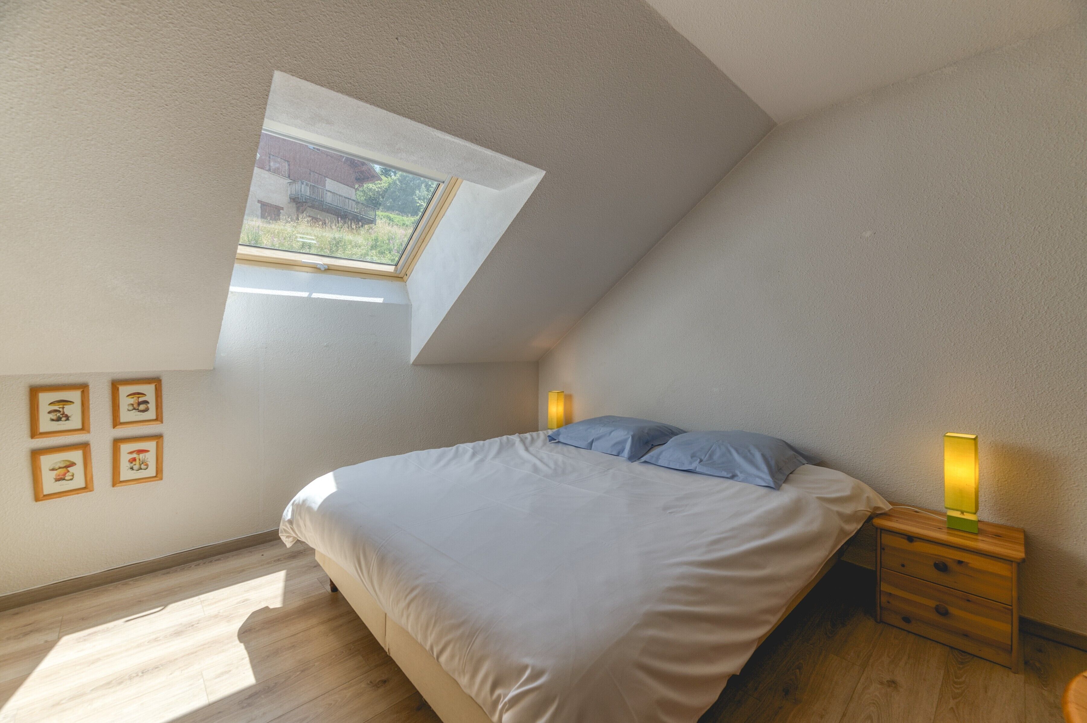 Une chambre à coucher avec un puits de lumière, un lit, une table de chevet et une lampe fixée au mur.